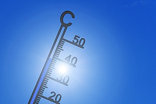 ein Thermometer, dass die Gradzahl von ca. 38° anzeigt. Dahinter ein blauer Himmel.