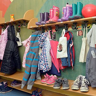 Eine Garderobe an der Wand mit vielen bunten Mänteln