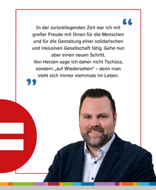 Ein Mann mit braunem Haar, einer blauen Jacke und einem weißen Hemd vor einer weißen Wand