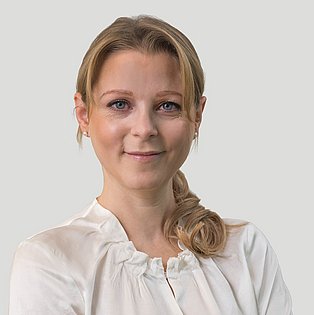 blonde Frau mit weißer Bluse vor hellgrauem Hintergrund